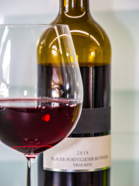 一杯红酒，背景是一瓶模糊的蓝色葡萄牙红酒图片下载