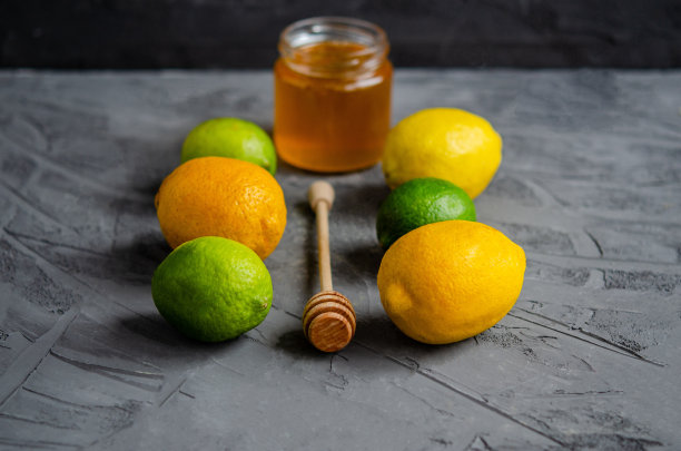 柑橘类水果柠檬和酸橙，生姜根，新鲜蜂蜜在一个罐子里在一个黑色的背景。图片下载