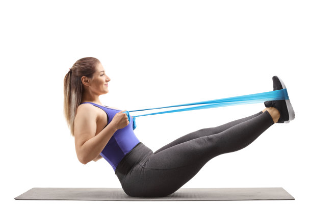 一名年轻女子在运动垫上用腿拉橡皮筋图片下载