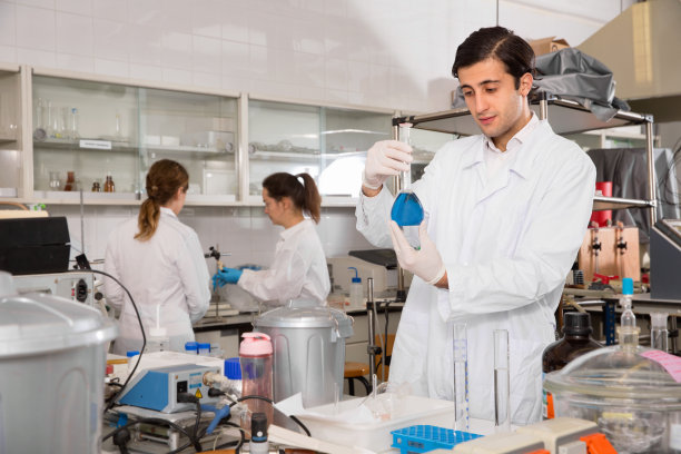 专注于在化学实验中使用试管中的试剂的年轻实验室技术员图片下载