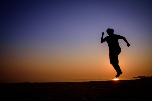 日落时分，海滩上奔跑的男人的剪影图片下载