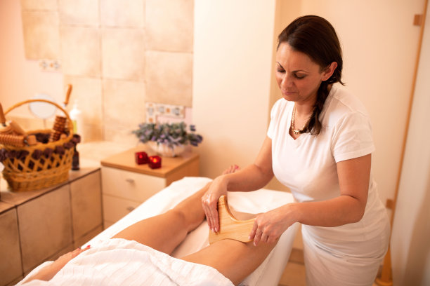 按摩师拿着一个木制工具，按摩她的客户的大腿图片下载