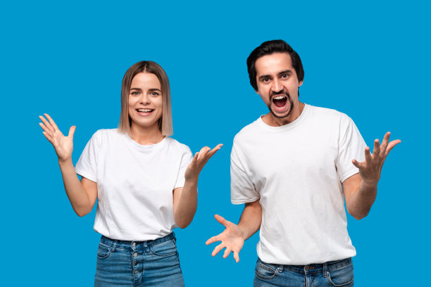 表达成功情感的幸福夫妇。年轻的金发女子和留着小胡子、穿着白色t恤和蓝色牛仔裤的大胡子男子获胜。模型孤立地站在蓝色背景上。图片下载