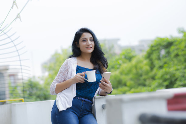 女人放松在阳台上拿着一杯咖啡或茶库存照片图片下载