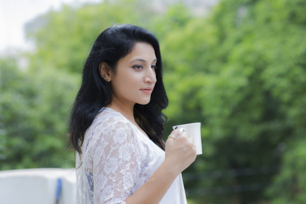 女人放松在阳台上拿着一杯咖啡或茶库存照片图片下载