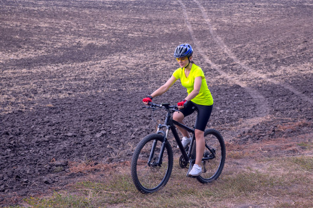 穿着黄色衣服的美丽女孩在大自然中骑自行车。图片下载
