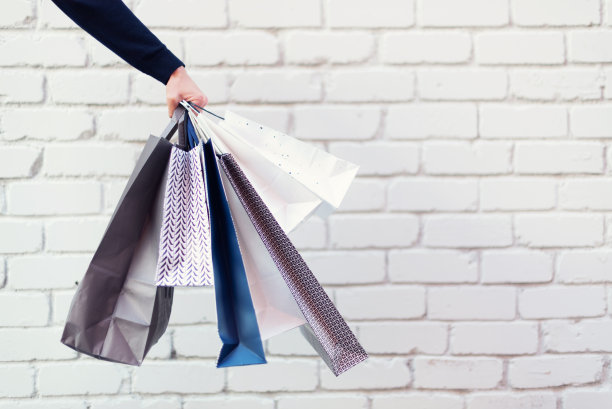 男手拿着一堆购物袋与购买靠近砖背景。副本的空间。打折，打折，黑色星期五的概念。购物中心及专卖店图片下载