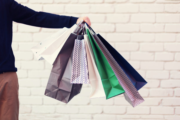 男手拿着一堆购物袋与购买靠近砖背景。副本的空间。打折，打折，黑色星期五的概念。购物中心及专卖店图片下载