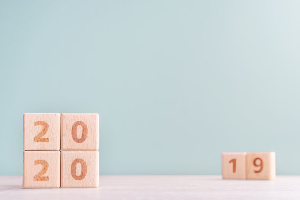 2020年和2019年新年倒计时设计理念——木桌上的木块立方体，低饱和度的绿色背景。图片下载