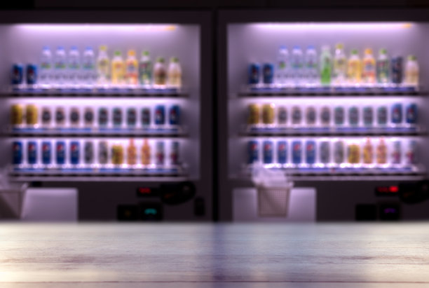 模糊的自动售货机和与彩色软饮料的空木桌图片下载