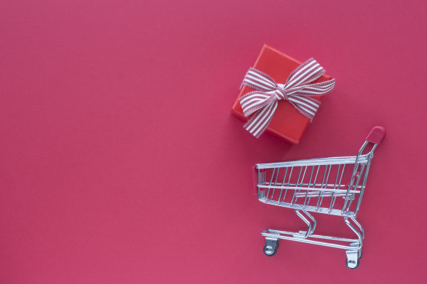 红色背景上的小购物车和红色礼品盒。顶视图的卡片图片下载