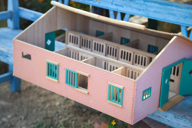 一个木制的娃娃屋，放在一个质朴的蓝色长凳上图片下载