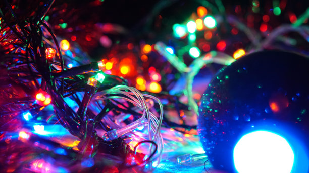 圣诞五彩缤纷，新年虚掩霓虹彩灯。模糊的照片背景与闪烁的灯光从花环和球。装饰用鲜艳的霓虹灯、粉红、蓝色、黄色闪烁的灯光图片下载