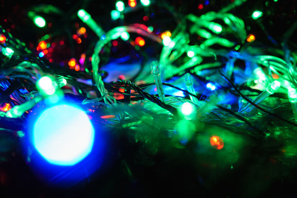 圣诞五彩缤纷，新年虚掩霓虹彩灯。模糊的照片背景与闪烁的灯从纠结的花环。装饰用鲜艳的霓虹灯粉、蓝、红、绿闪烁的灯光图片下载