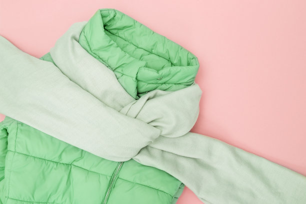 秋天的平铺与温暖的服装趋势颜色在粉红色的背景。鲜艳的时尚女装。羽绒服新薄荷色，纺织宽围巾。前视图。平的。图片下载