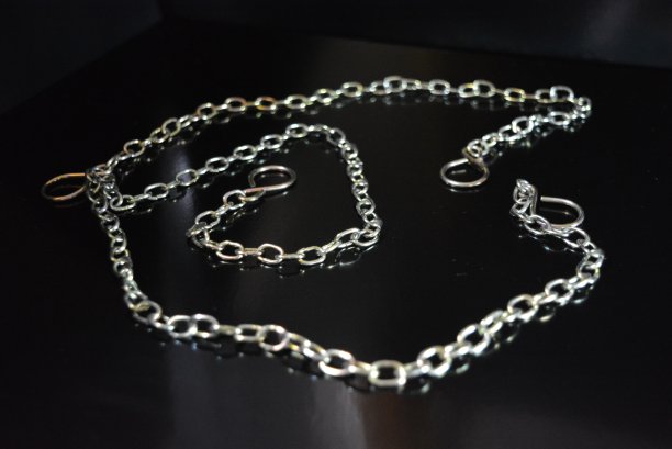 时尚的金属链作为一个有趣的颜色配件位于一个光滑的黑色表面。图片下载