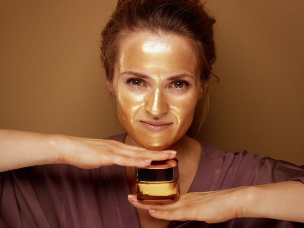 现代家庭主妇用金色的化妆面膜捧霜图片下载