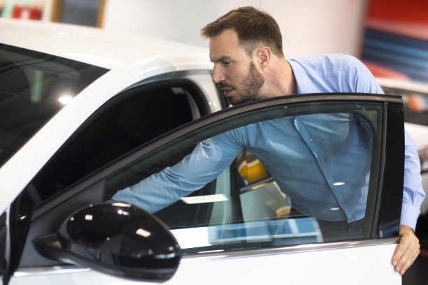 一名男子在汽车展示厅打开一辆新车的门，把手伸进去图片下载