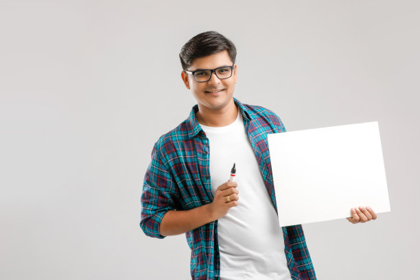 印度/亚洲青年在白色背景的空白招牌上写字图片下载