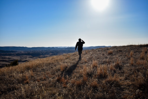 一个人的剪影走过起伏的山丘图片下载