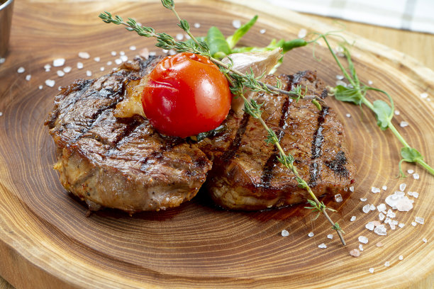 近距离观看美味的烤牛排在木板上。由熟牛肉、香草和蔬菜组成。食物的照片背景。有选择性的重点图片下载