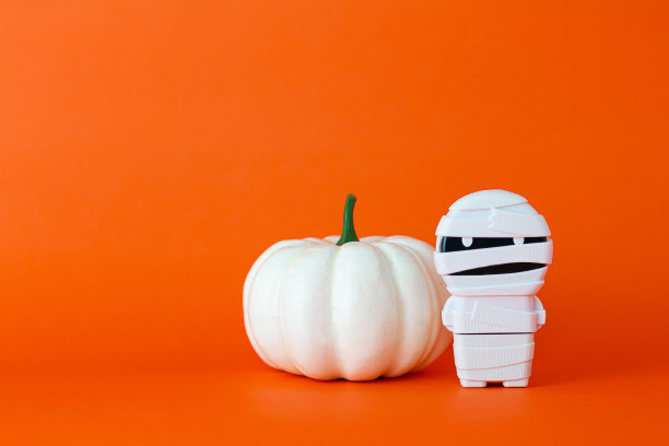 白色南瓜与木乃伊在橙色的背景与拷贝空间，万圣节的概念。图片下载