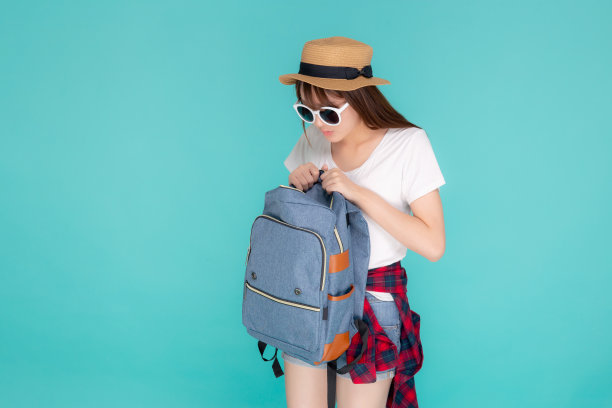 美丽的肖像年轻的亚洲女人戴太阳镜和帽子微笑打开背包旅行夏季旅行假期在假期孤立的蓝色背景，快乐的亚洲女孩是自信的包。图片下载