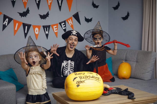 快乐的家庭妈妈和孩子们在黑暗的家里庆祝万圣节。图片下载