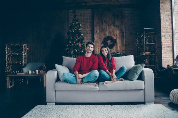 全长照片浪漫的配偶微笑坐在沙发与新年装饰照明灯有圣诞假期圣诞假期图片下载