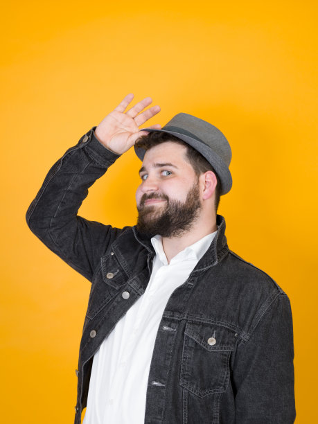 戴着帽子的酷男人前面是黄色的，橙色的背景图片下载