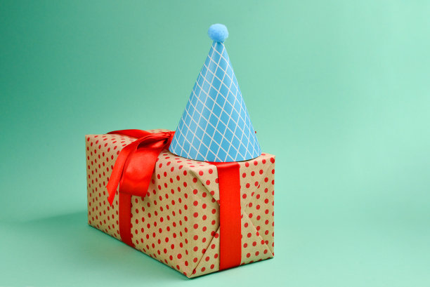 蓝色的生日帽和一份绿色背景的礼物。文字或设计空间。图片下载