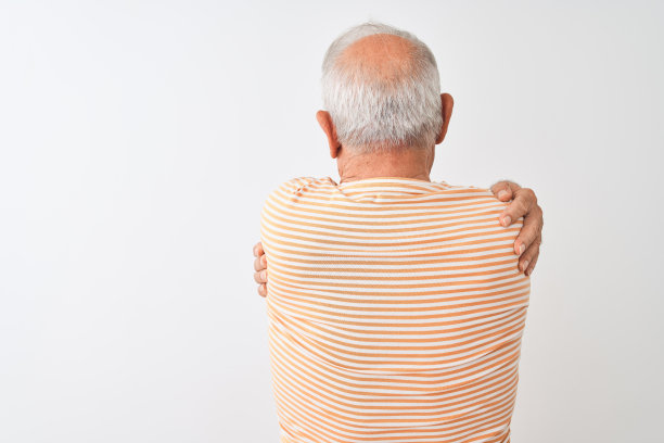 白发苍苍的老人穿着条纹t恤站在孤立的白色背景下，从背后拥抱着自己快乐和积极。爱自己，关心自己图片下载