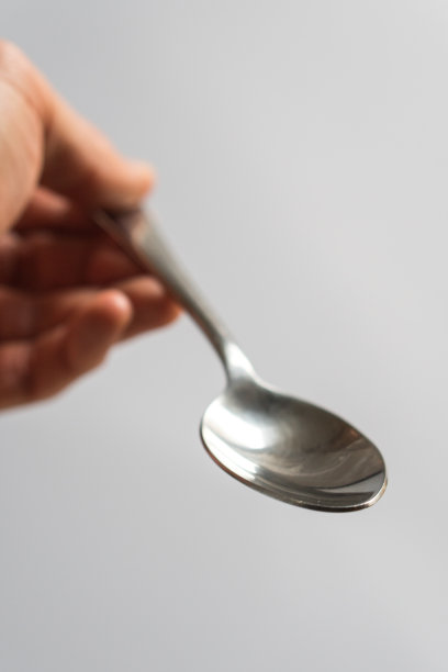 一只手拿着空的不锈钢勺子图片下载