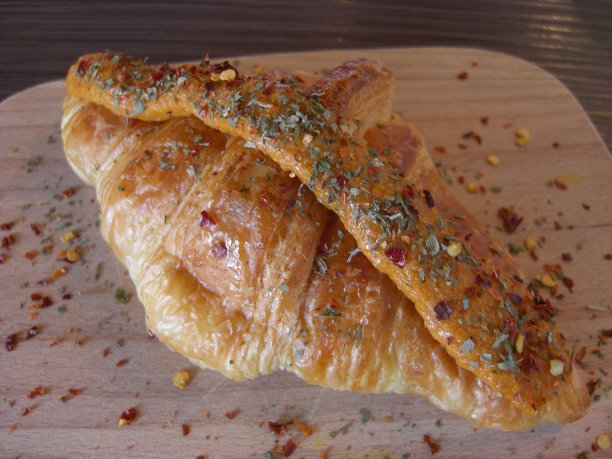 牛角面包撒上香草和香料，放在木板上图片下载