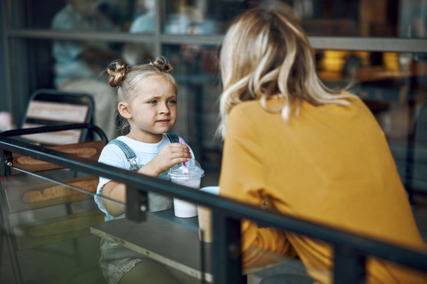 女孩喝奶昔和看母亲库存照片图片下载