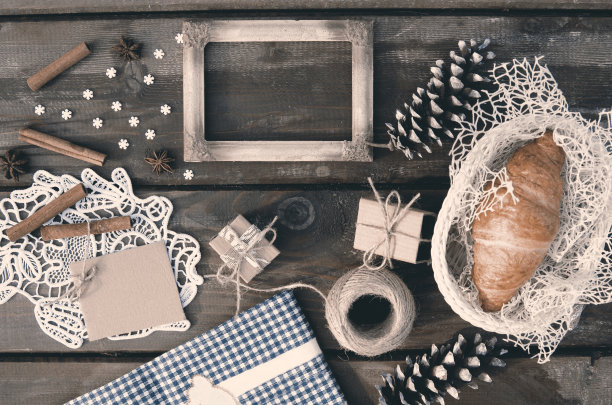 秋冬背景的乡村照片空框，礼盒，丝带，蓝布，松果，花边，肉桂棒，雪花，八角香料和新鲜牛角在篮子里。以上平躺图片下载