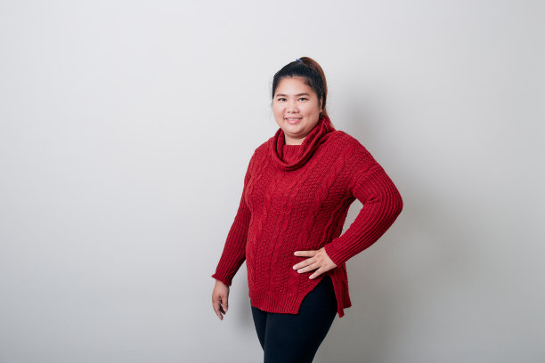快乐的年轻女子亚洲在冬天的红色毛衣在工作室明亮的灰色背景图片下载