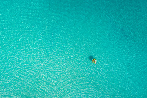 鸟瞰图，苗条的女人在透明的塞舌尔绿松石海游泳圈甜甜圈。夏日的海景带着少女，美丽的海浪，五颜六色的水。无人机俯视图图片下载