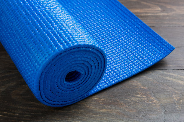 木制背景上的蓝色瑜伽垫。瑜伽的设备。健康生活方式、运动和饮食的概念图片下载