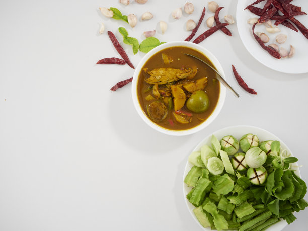 泰国菜。由多种香料制成的风味浓郁的南咖喱，配上新鲜蔬菜放在餐桌上图片下载
