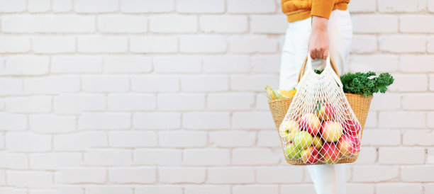 女孩拿着装满苹果的可重复使用网袋，草篮里装着有机蔬菜。横幅。副本的空间。秋天的收获。可持续的生态的生活方式。零浪费，无塑料的概念。图片下载
