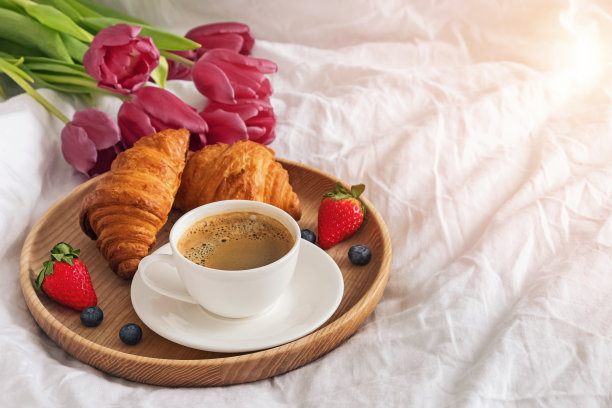 咖啡、牛角面包和白色床单上的鲜花特写图片下载