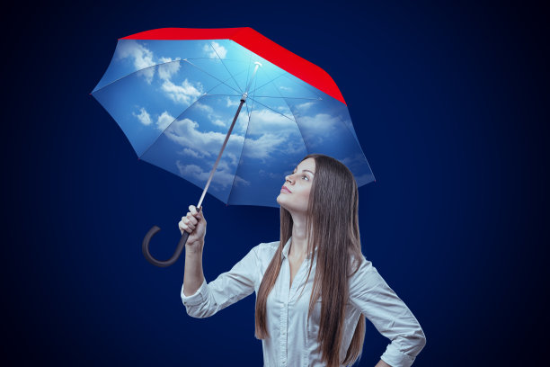 年轻女子与天空设计伞在深蓝色的背景图片下载