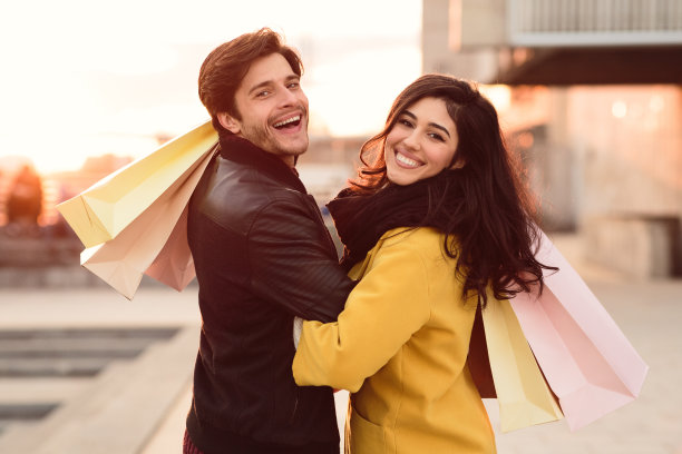 幸福的新婚夫妇提着购物袋，对着镜头微笑图片下载