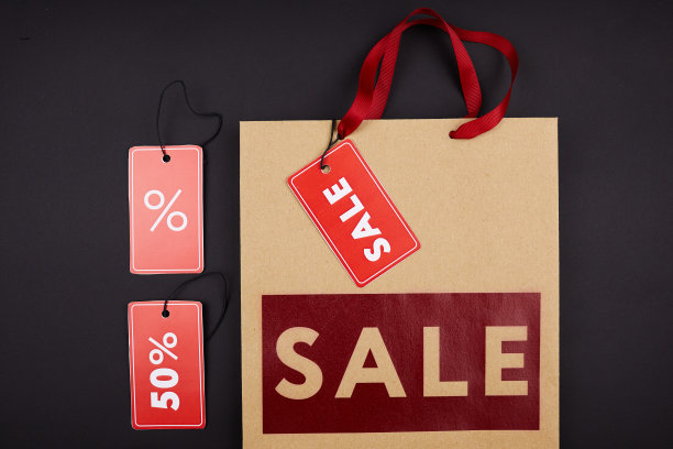 高角度的标签出售和纸袋与红色的题字在黑色的背景图片下载