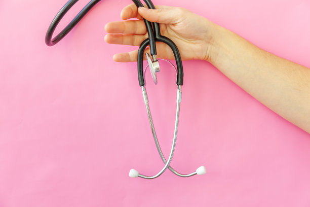 简单简约的设计，女性手持医疗设备，听诊器或听诊器孤立在时尚粉粉背景图片下载