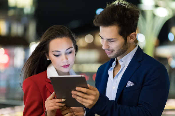 一对商务人士晚上在现代城市环境下使用平板电脑图片下载
