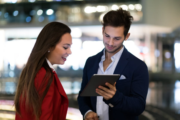 一对商务人士晚上在现代城市环境下使用平板电脑图片下载
