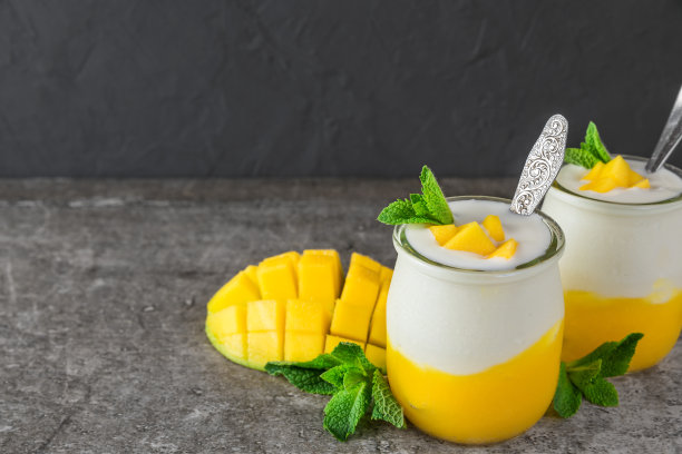 芒果果酸奶与新鲜薄荷杯与勺子在黑色混凝土背景。健康的早餐图片下载