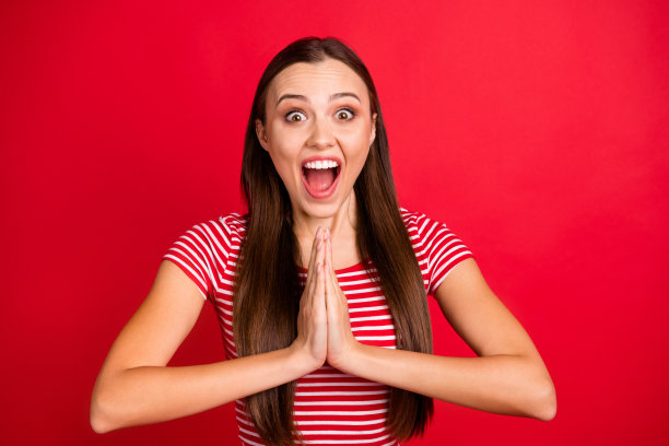 期待等待的照片迷人的大笑尖叫的女孩穿着条纹t恤在等待的东西，而孤立的红色背景图片下载